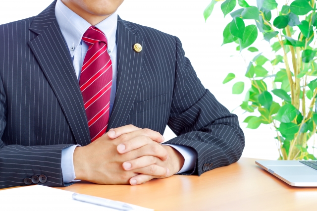 手を組んでいる男性の弁護士