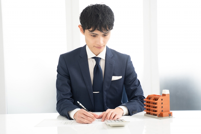 家の模型と査定する男性