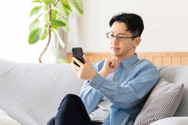 スマホを見て悩む男性