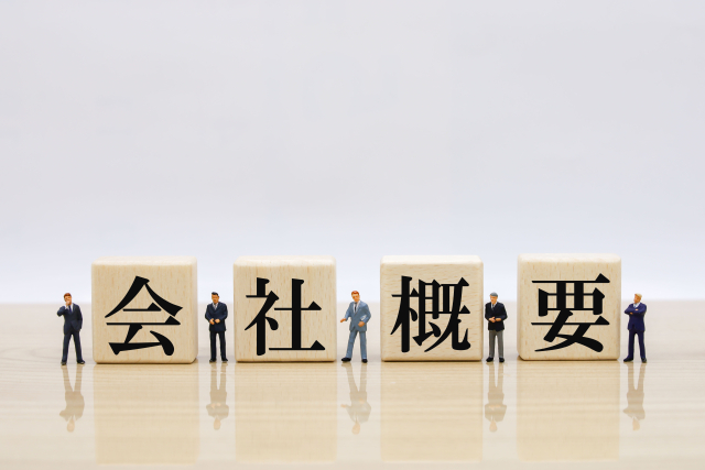 会社概要と書かれたブロックとミニチュアのビジネスマン