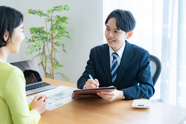 不動産会社の営業マンと話す女性客